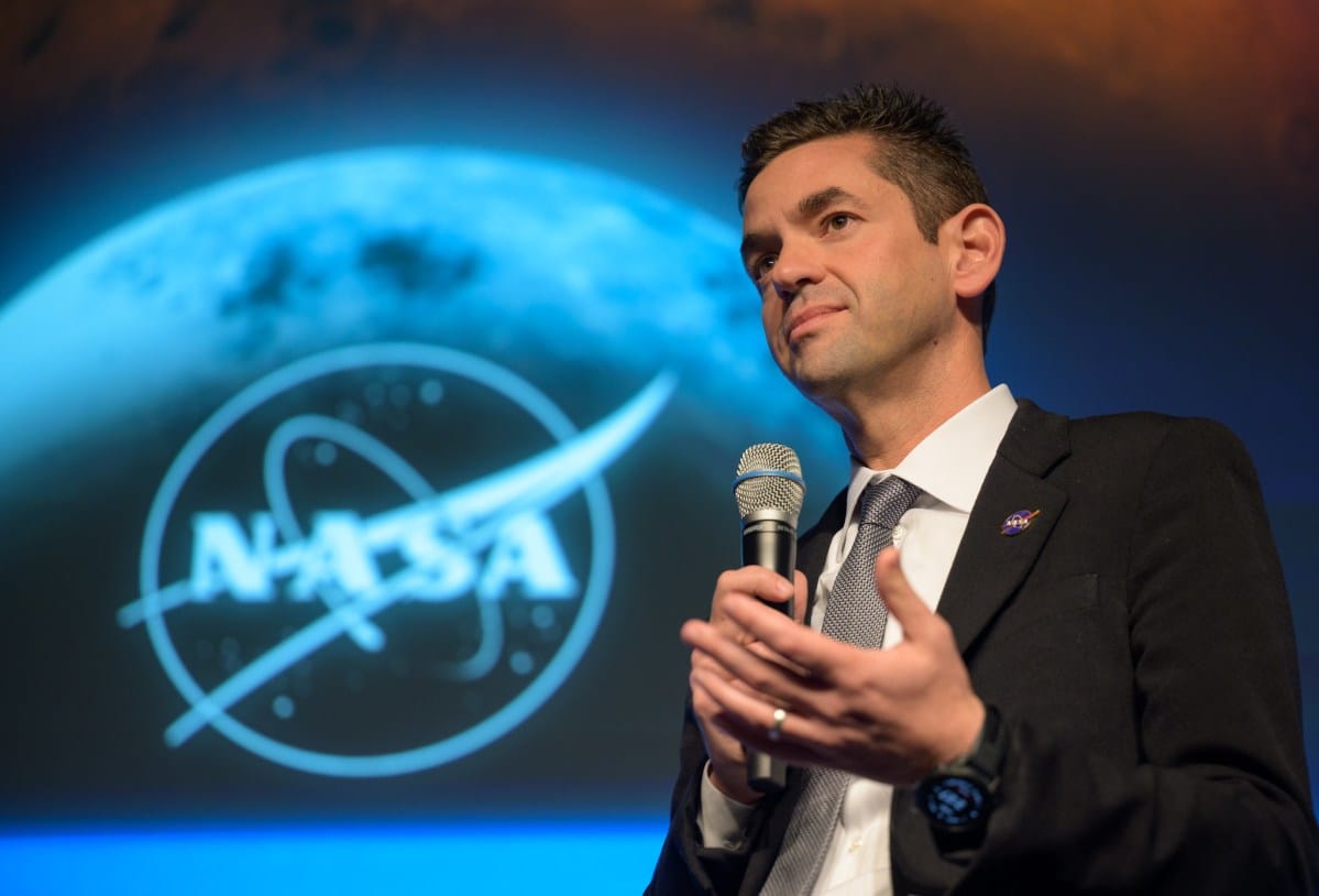NASA Administrator Jared Isaacman speaking in front of a NASA logo